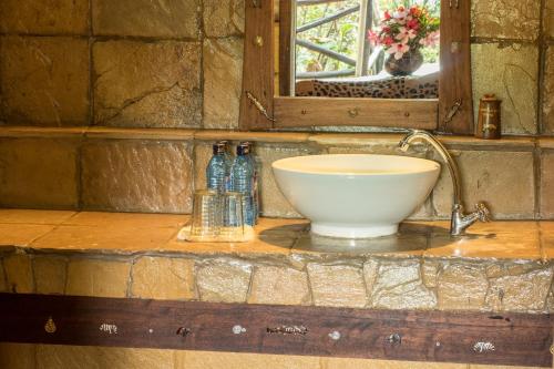 a bathroom counter with a bowl sink and a mirror at Rhino Watch Safarilodge in Mweiga
