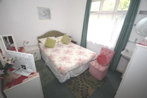 a small bedroom with a bed and a chair at El Tabora Guest House in St Peter Port