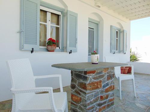 a patio with white chairs and a stone table at George's Place Sifnos - apartments in Apollonia