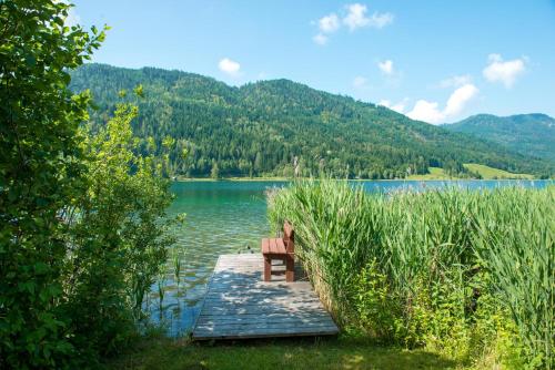 a bench sitting on a dock in front of a lake at Haus Waldklause in Techendorf