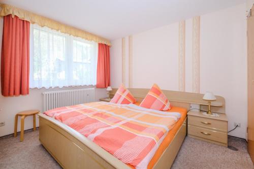 Schlafzimmer mit einem großen Bett mit orangefarbener und weißer Bettwäsche in der Unterkunft Ferienhaus Harzidyll in Schierke