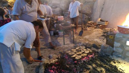 a group of people standing around a grill with food at Apartments Stengl in Rab