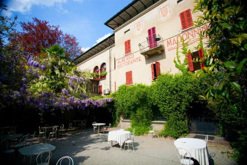 a building with tables and chairs and purple flowers at Albergo Ristorante Madonnina in Cantello