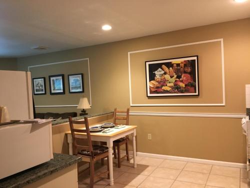 une salle à manger avec une table et un tableau mural dans l'établissement Whitman Motor Lodge, à Huntington