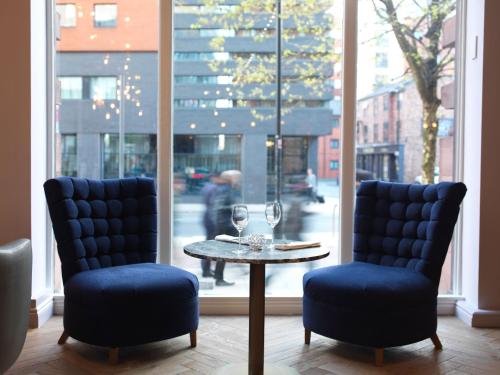 two chairs and a table with wine glasses on it at ABode Manchester in Manchester