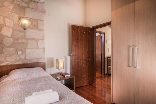 a bedroom with a bed and a stone wall at Spilia Village Hotel & Villas in Spiliá