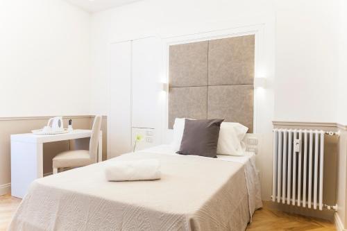 biała sypialnia z łóżkiem i krzesłem w obiekcie Margherita Suites w Rzymie
