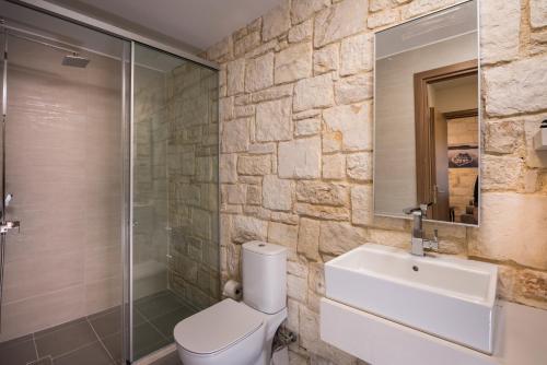 a bathroom with a toilet and a sink and a shower at Spilia Village Hotel & Villas in Spiliá