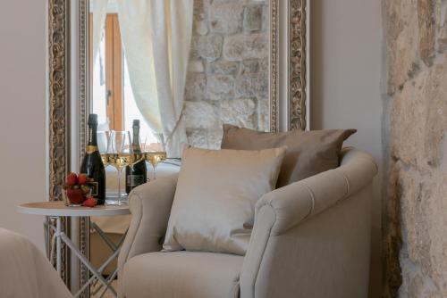 ein Wohnzimmer mit einem Stuhl und einem Tisch mit Weingläsern in der Unterkunft Jupiter Lux Rooms in Split