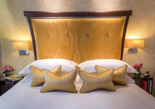 a bed with a large wooden headboard and four pillows at Ten Manchester Street Hotel in London