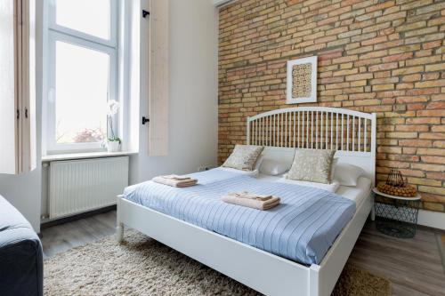 a bedroom with a white bed with a brick wall at Buda Castle Apartment in Budapest