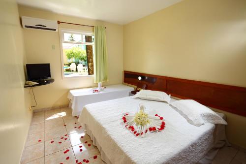 a bedroom with a bed with a flower arrangement on it at Boulevard da Praia Apart Hotel in Porto Seguro