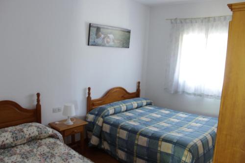 1 dormitorio con 2 camas y ventana en Casa Rural El Tejar, en Higuera de la Sierra