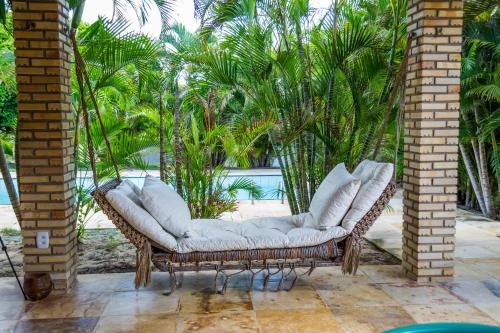 a wicker chair with white pillows on a patio at Refúgios Parajuru - Villa Cristiano in Parajuru