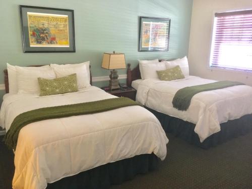 1 dormitorio con 2 camas con sábanas blancas y ventana en Whitman Motor Lodge, en Huntington