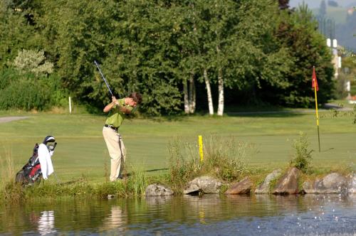 a man holding a golf club next to a body of water at Sporthotel Radstadt in Radstadt