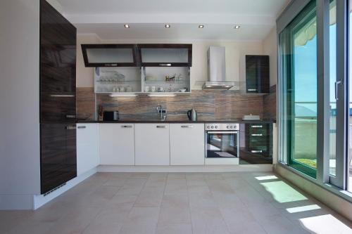 a kitchen with white cabinets and a large window at Apia Residence in Budva