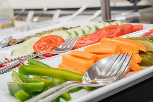 a plate of vegetables on a table with forks and spoons at Hotel Rose in Bretzfeld