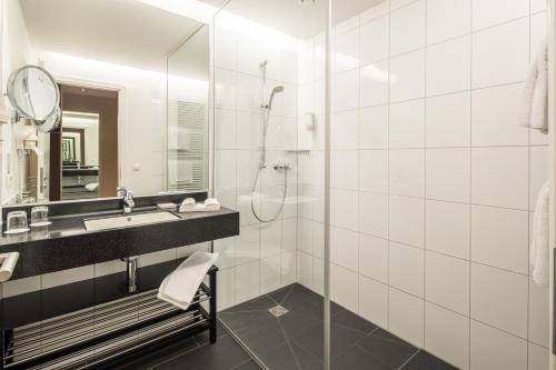 een badkamer met een douche, een wastafel en een spiegel bij Hotel Rose in Bretzfeld