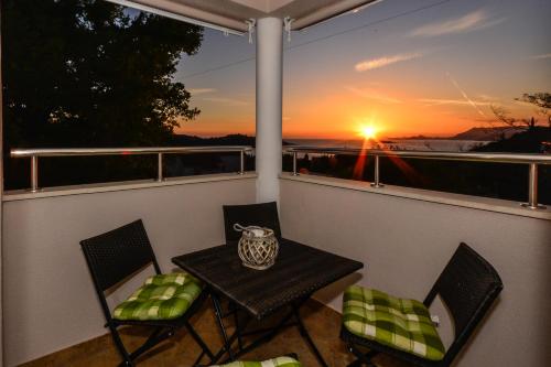 a table and chairs on a balcony with a sunset at A&M Cavtat, sunset 3 bedrooms apartment with parking in Cavtat