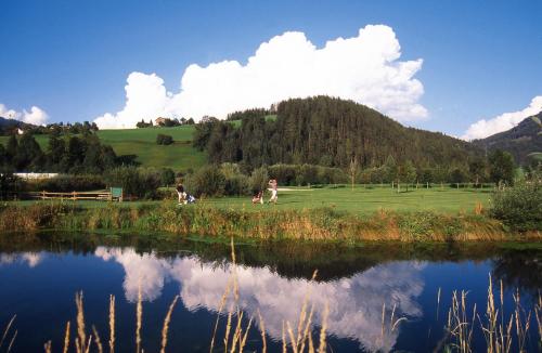a couple of people walking in a field next to a lake at Sporthotel Radstadt in Radstadt