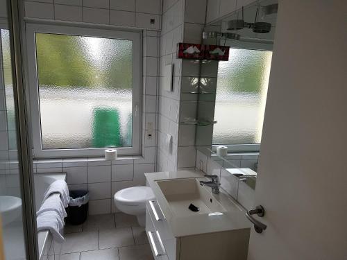 a bathroom with a sink and a toilet and two windows at Hotel Pegasus in Munich
