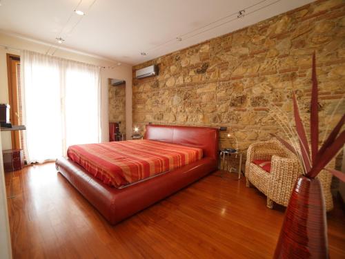 a bedroom with a red bed and a stone wall at Villa Anna in Santa Teresa di Riva