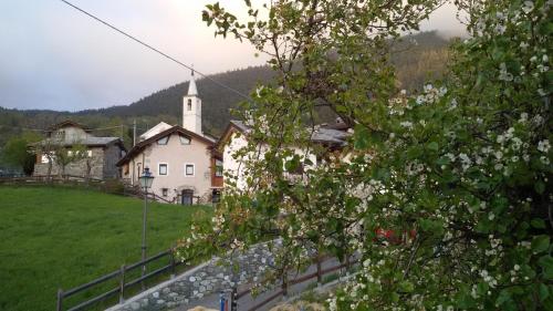 a church with a steeple in a field with a tree at Taverna Semon in Verrayes
