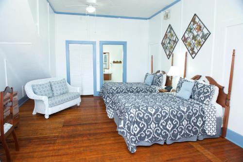 a bedroom with a bed and a couch and a chair at The Great House Inn in Belize City