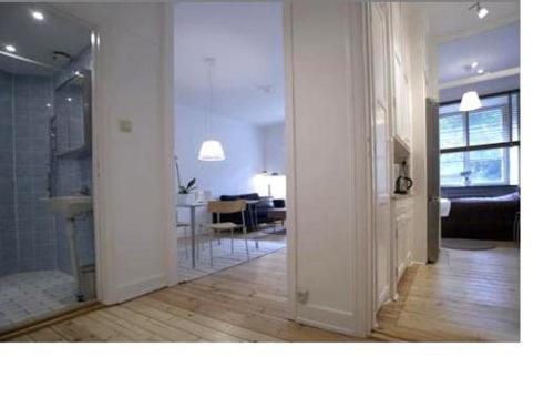 een woonkamer met witte muren en een kamer met een hal bij Stockholm Checkin Apartment Fridhemsplan in Stockholm
