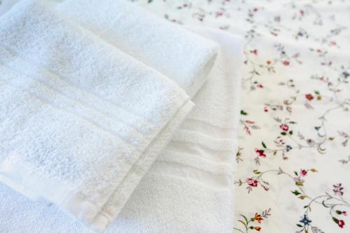 a white towel sitting on a bed with flowers at Azzurro B&B in Cefalù