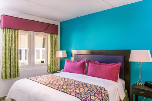 een slaapkamer met blauwe muren en een bed met roze kussens bij MVC Eagle Beach in Palm-Eagle Beach