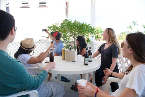 een groep mensen die rond een tafel zitten met wijnflessen bij The Great House Inn in Belize City