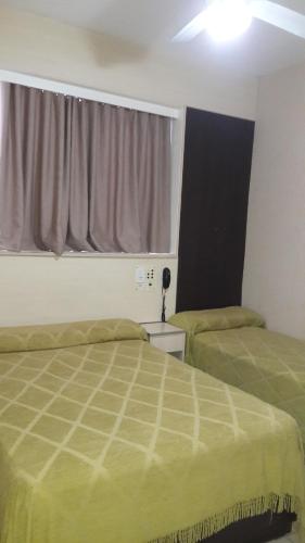 a bedroom with two green beds and a window at Hotel Micro in Rosario