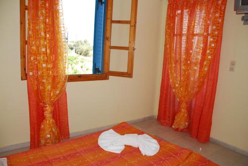 a room with a bed with a bow tie on it at Koulas Pension - Red Lake in Agios Prokopios