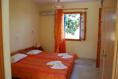 a bedroom with two beds and a window at Koulas Pension - Red Lake in Agios Prokopios