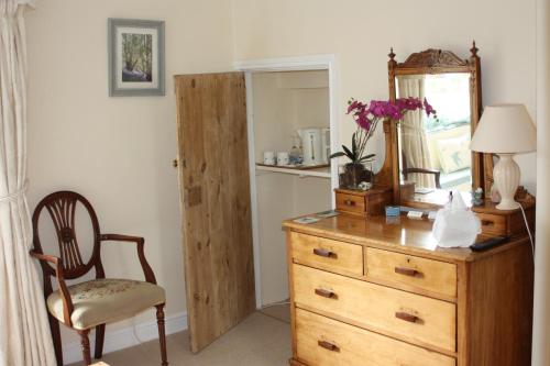 a dresser with a mirror and a chair in a room at Firs Farm B&B in Masham