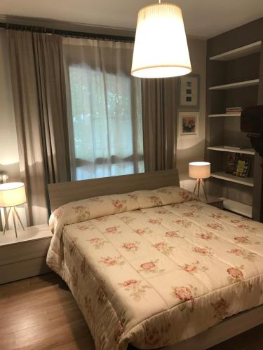 1 dormitorio con 1 cama con colcha de flores y 2 lámparas en Monolocale con giardino, en San Benedetto del Tronto