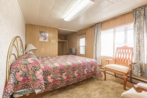 a bedroom with a bed and a chair and a window at Dayton Motel in Dayton