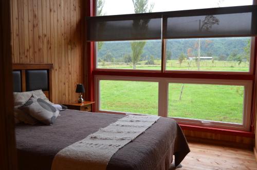 1 dormitorio con cama y ventana grande en El Descanso del Quijote, en Riñinahue