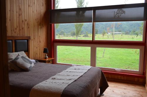 ein Schlafzimmer mit einem Bett und einem großen Fenster in der Unterkunft El Descanso del Quijote in Riñinahue