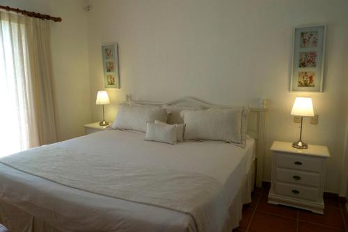 a bedroom with a large white bed with two lamps at The Golf Suites in Punta Cana