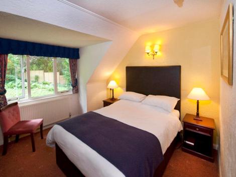 a hotel room with a large bed and two lamps at Hunters Hall Inn by Greene King Inns in Kingscote