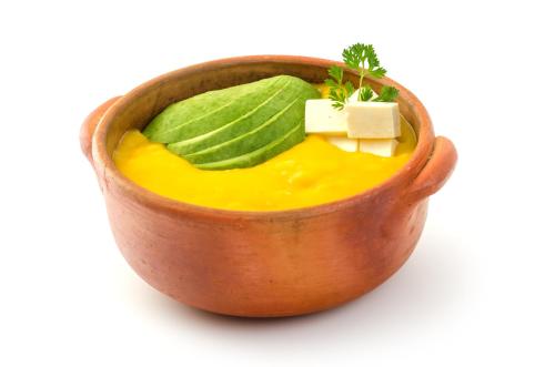 a bowl of soup with a stick of cheese and green leaves at Hotel Hacienda Abraspungo in Riobamba