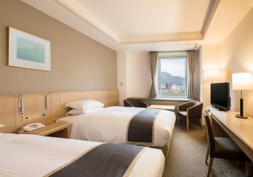 a hotel room with two beds and a desk at Sapporo Park Hotel in Sapporo