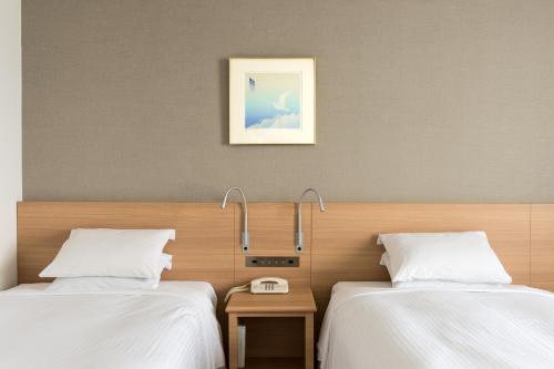 two beds in a hotel room with white sheets at Sapporo Park Hotel in Sapporo