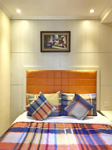 a bedroom with a bed with a orange headboard and pillows at Ravarine Suite Apartment in Jakarta