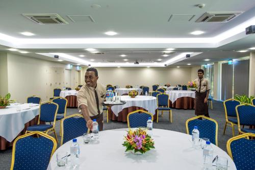 a man standing at a table in a banquet hall at Heritage Park Hotel in Honiara