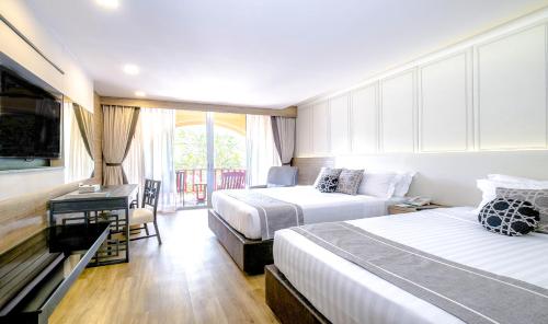 a hotel room with two beds and a desk at Phuket Graceland Resort and Spa in Patong Beach