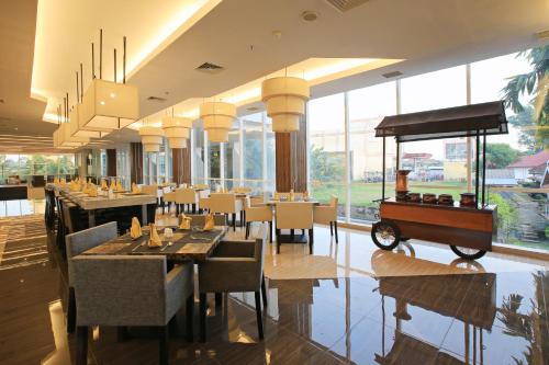 a restaurant with tables and chairs and a cart on the floor at Luminor Hotel Jambi Kebun Jeruk By WH in Jambi